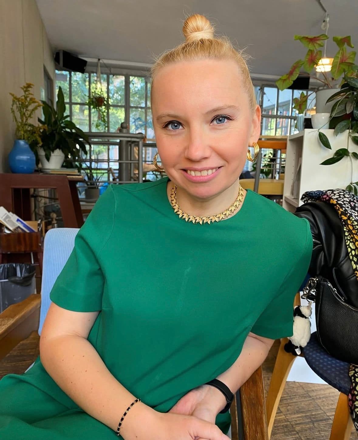 Anastasiia, personal stylist, in a green dress smiling in a café