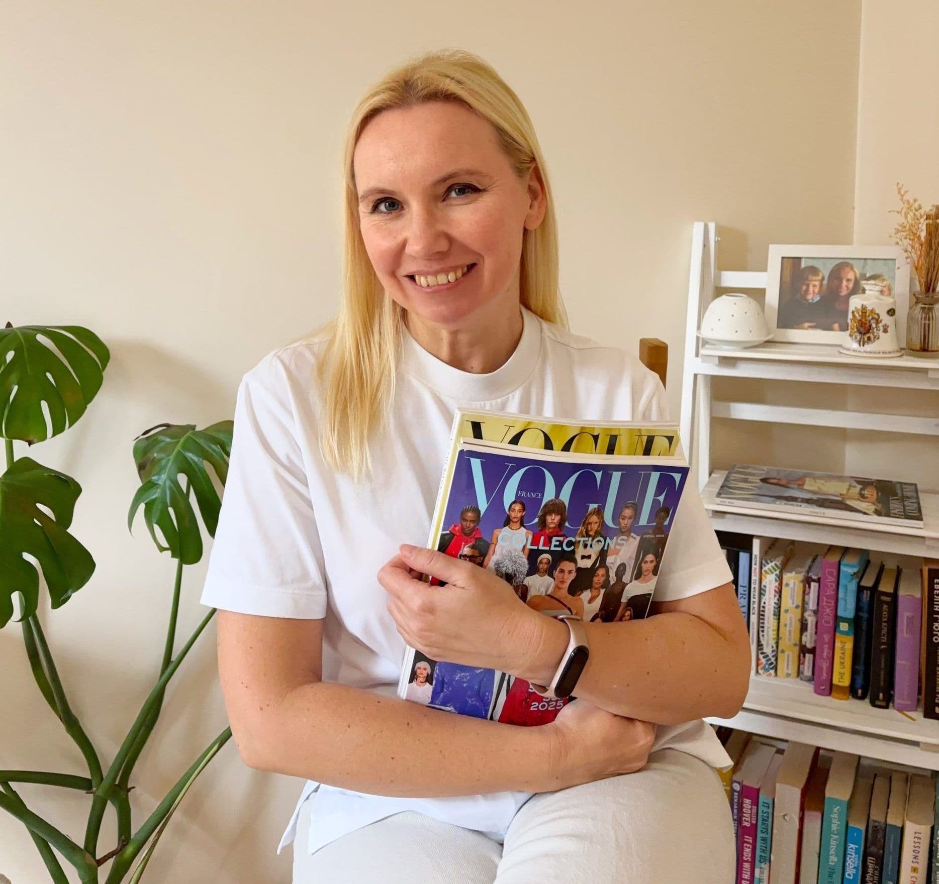 Anastasiia, personal stylist, smiling at home and holding a Vogue magazine