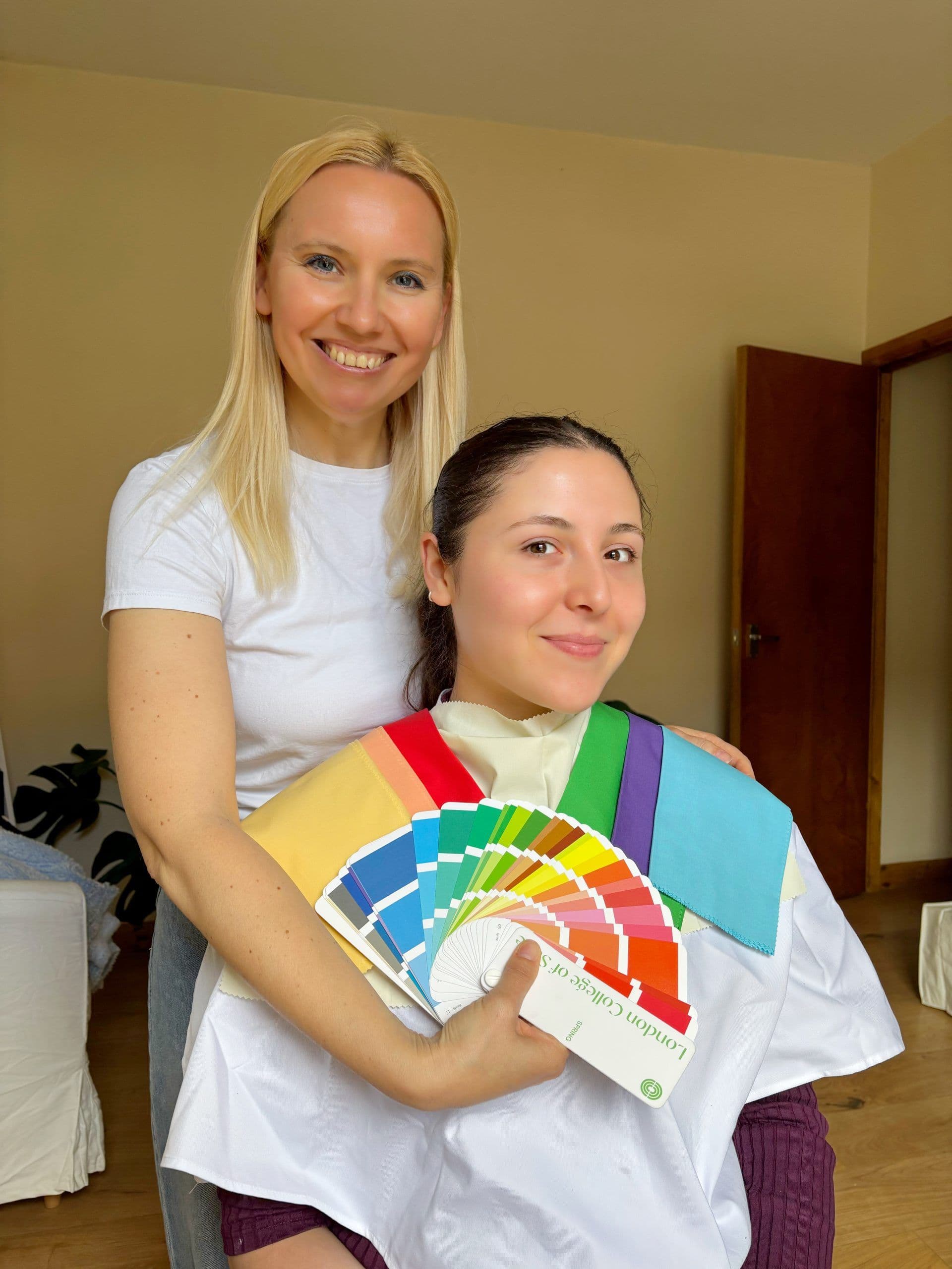 Anastasiia with a smiling client holding a fan of colour swatches during a colour analysis
